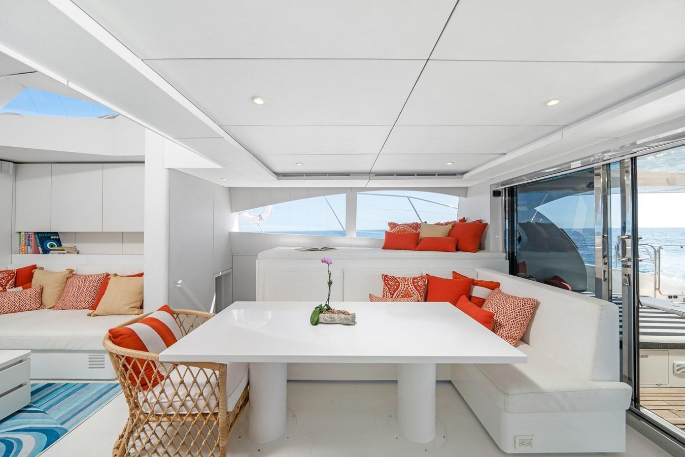 a white living room with a white table and red couches aboard ROYAL RITA Yacht for Sale
