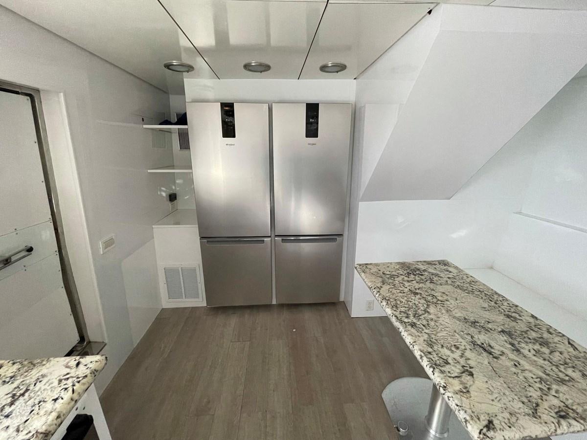 a kitchen with a fridge and a countertop aboard PACIFIC PEARL Yacht for Sale