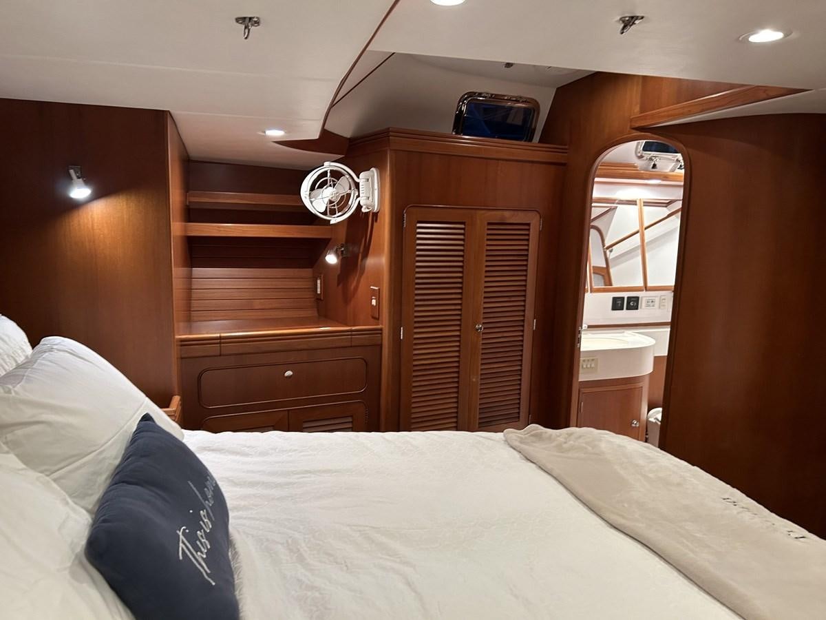 a bed with a white sheet and wooden cabinets aboard TRIUMPH Yacht for Sale