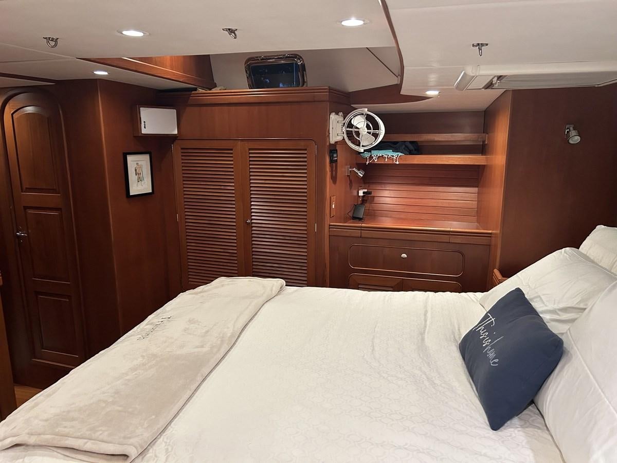 a bed with a white sheet and a blue pillow on it aboard TRIUMPH Yacht for Sale
