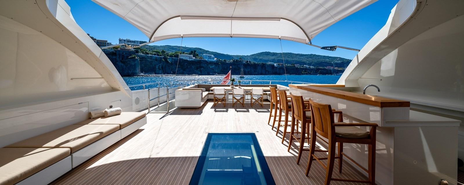 a room with a deck and chairs aboard QUANTUM H Yacht for Sale