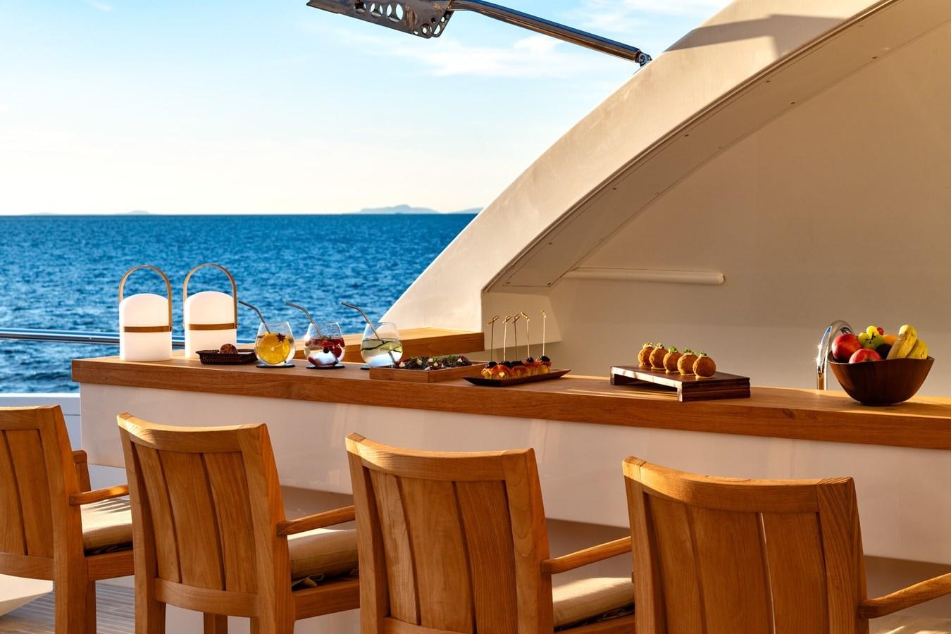 a table with chairs and a view of the ocean aboard QUANTUM H Yacht for Sale