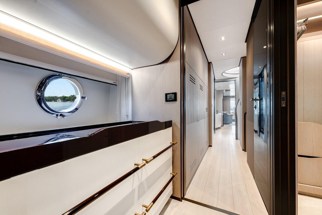 a hallway with a white wall and a round window aboard DAYBREAK Yacht for Sale