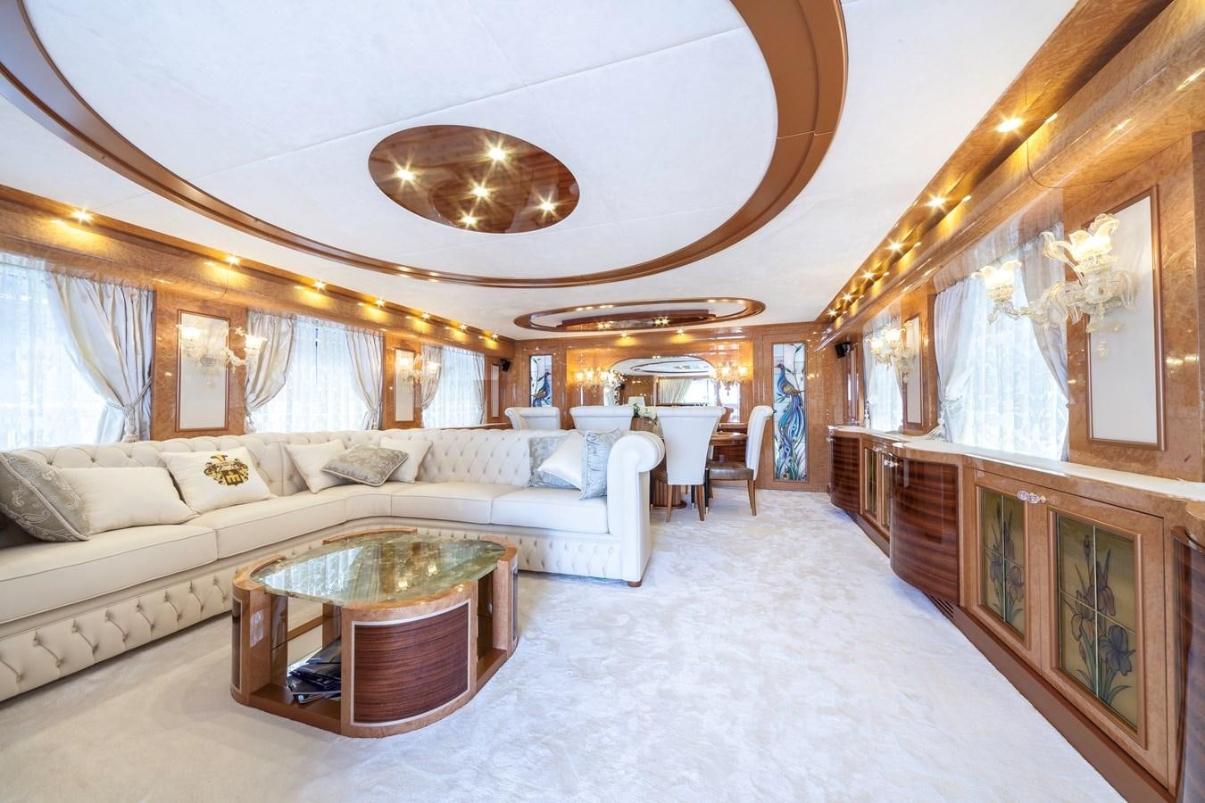 a large living room with a large white couch and a chandelier aboard DUCHESSA Yacht for Sale