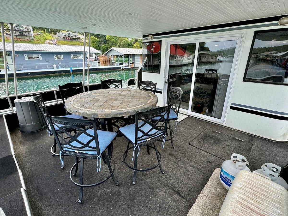 a table and chairs outside a bus aboard 2012 MAJESTIC 16 X 75WB HOUSEBOAT NLSD Yacht for Sale