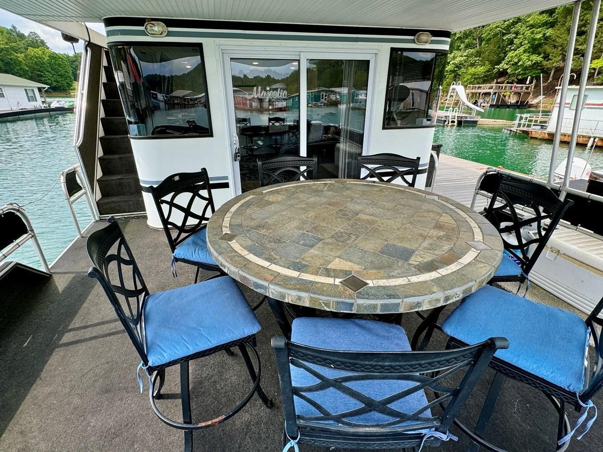 a table outside a house aboard 2012 MAJESTIC 16 X 75WB HOUSEBOAT NLSD Yacht for Sale