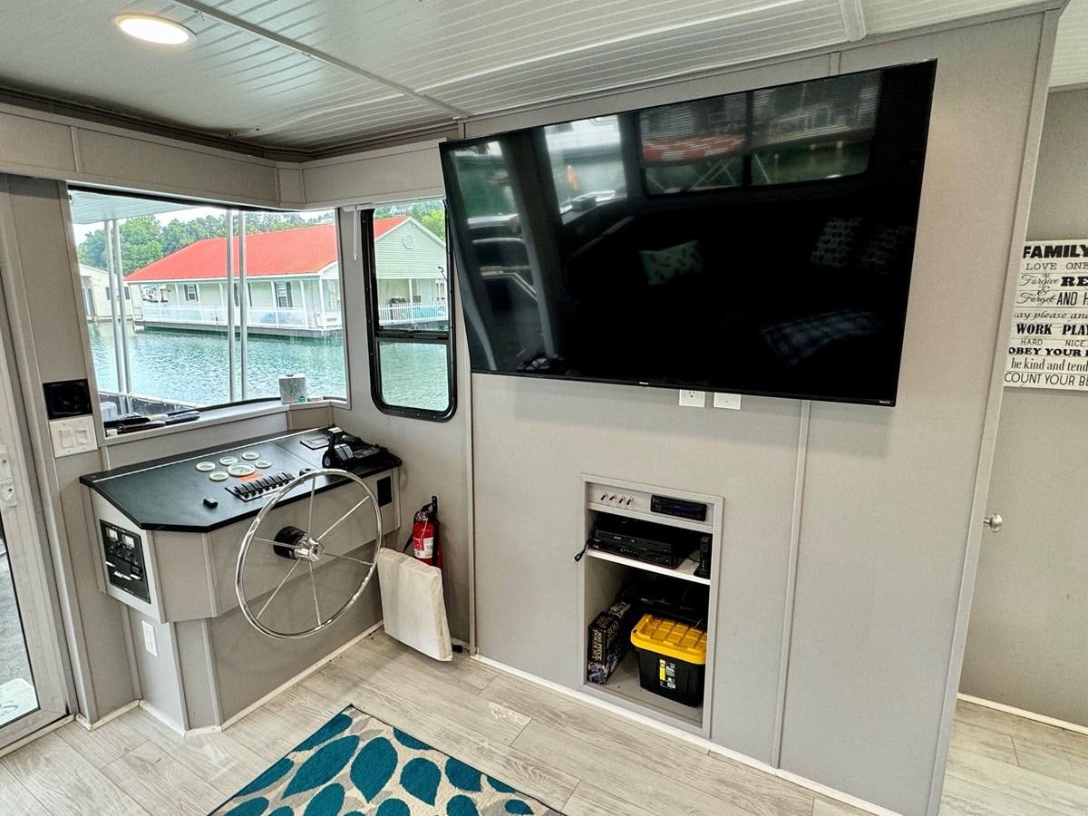 a room with a tv and a stove aboard 2012 MAJESTIC 16 X 75WB HOUSEBOAT NLSD Yacht for Sale