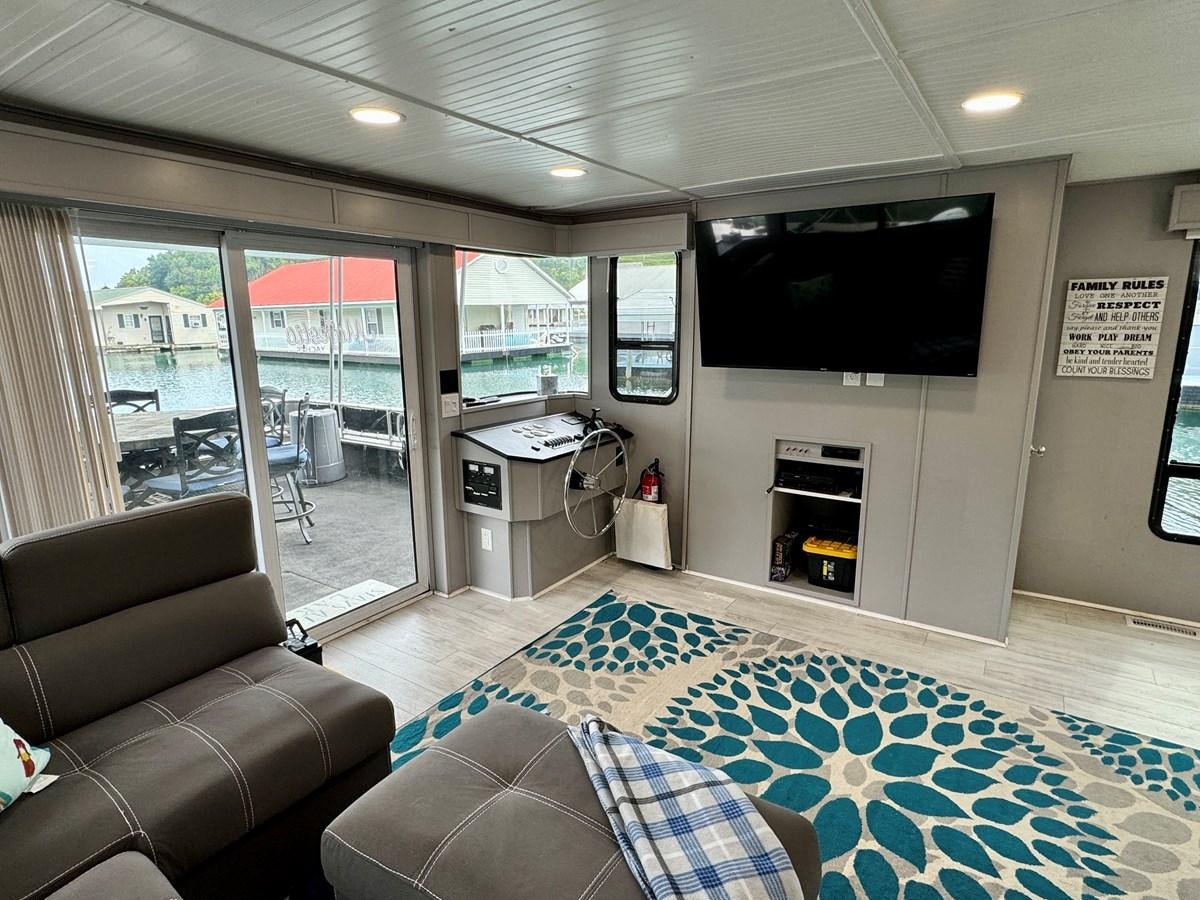 a living room with a large blue rug and a fireplace aboard 2012 MAJESTIC 16 X 75WB HOUSEBOAT NLSD Yacht for Sale