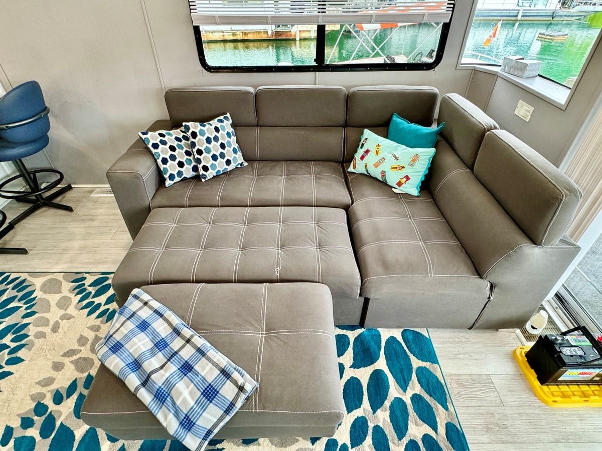 a couch with pillows aboard 2012 MAJESTIC 16 X 75WB HOUSEBOAT NLSD Yacht for Sale