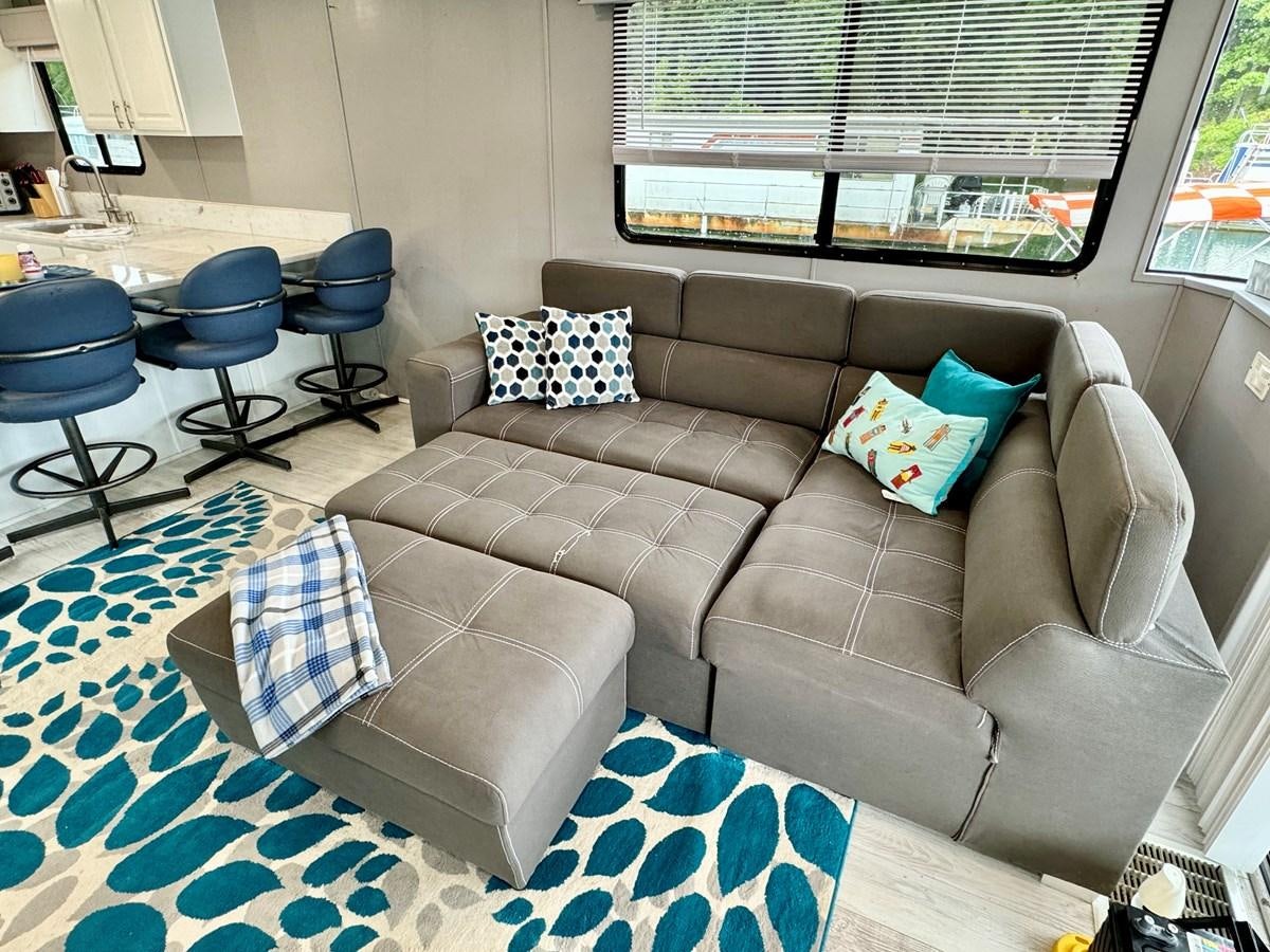 a couch with pillows and a chair aboard 2012 MAJESTIC 16 X 75WB HOUSEBOAT NLSD Yacht for Sale