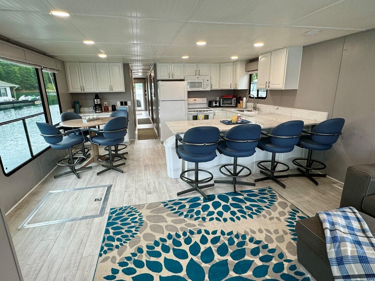a room with tables and chairs aboard 2012 MAJESTIC 16 X 75WB HOUSEBOAT NLSD Yacht for Sale