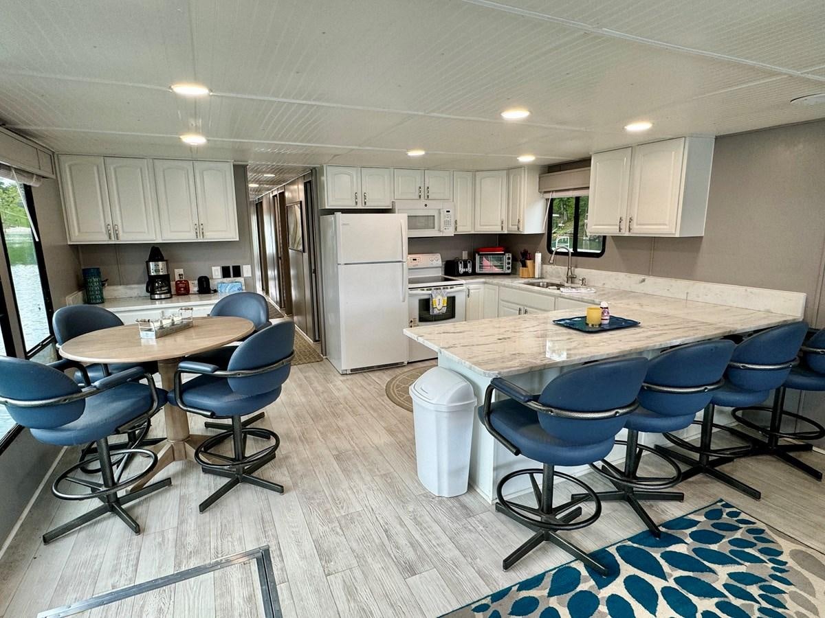 a kitchen with a table and chairs aboard 2012 MAJESTIC 16 X 75WB HOUSEBOAT NLSD Yacht for Sale