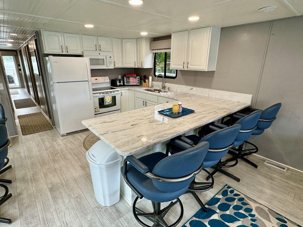 a kitchen with a table and chairs aboard 2012 MAJESTIC 16 X 75WB HOUSEBOAT NLSD Yacht for Sale