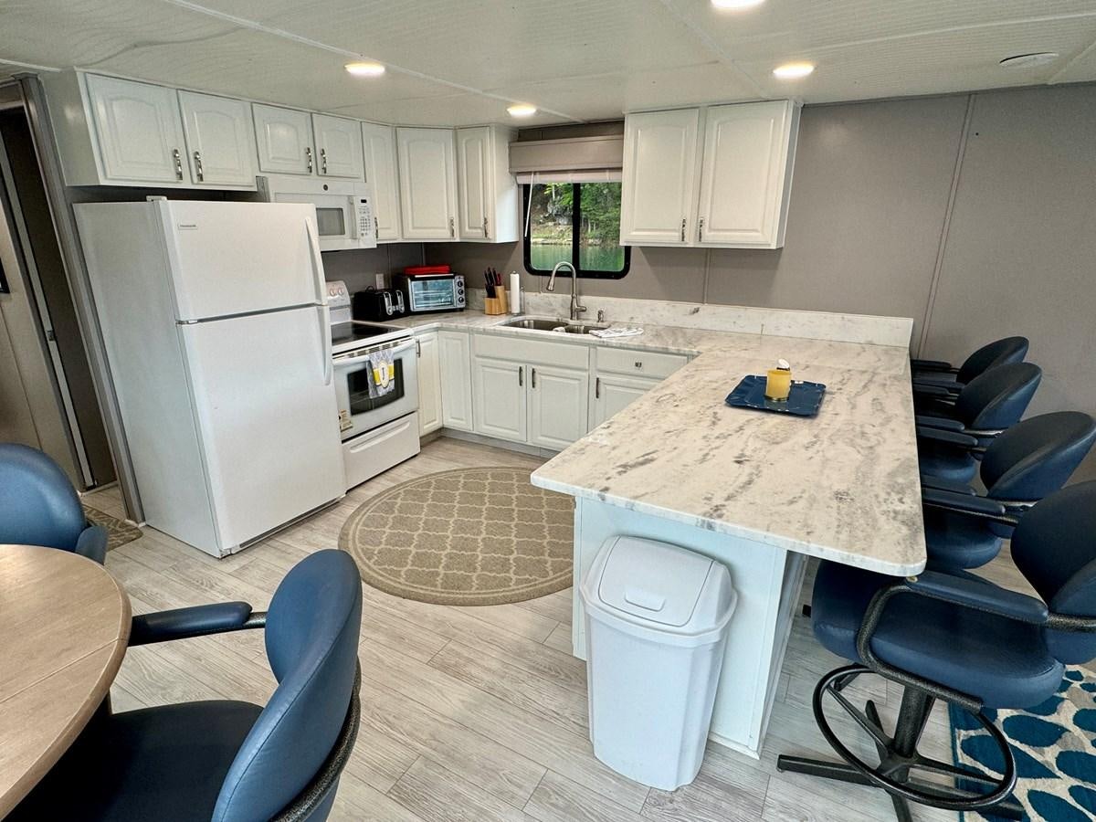 a kitchen with a table and chairs aboard 2012 MAJESTIC 16 X 75WB HOUSEBOAT NLSD Yacht for Sale