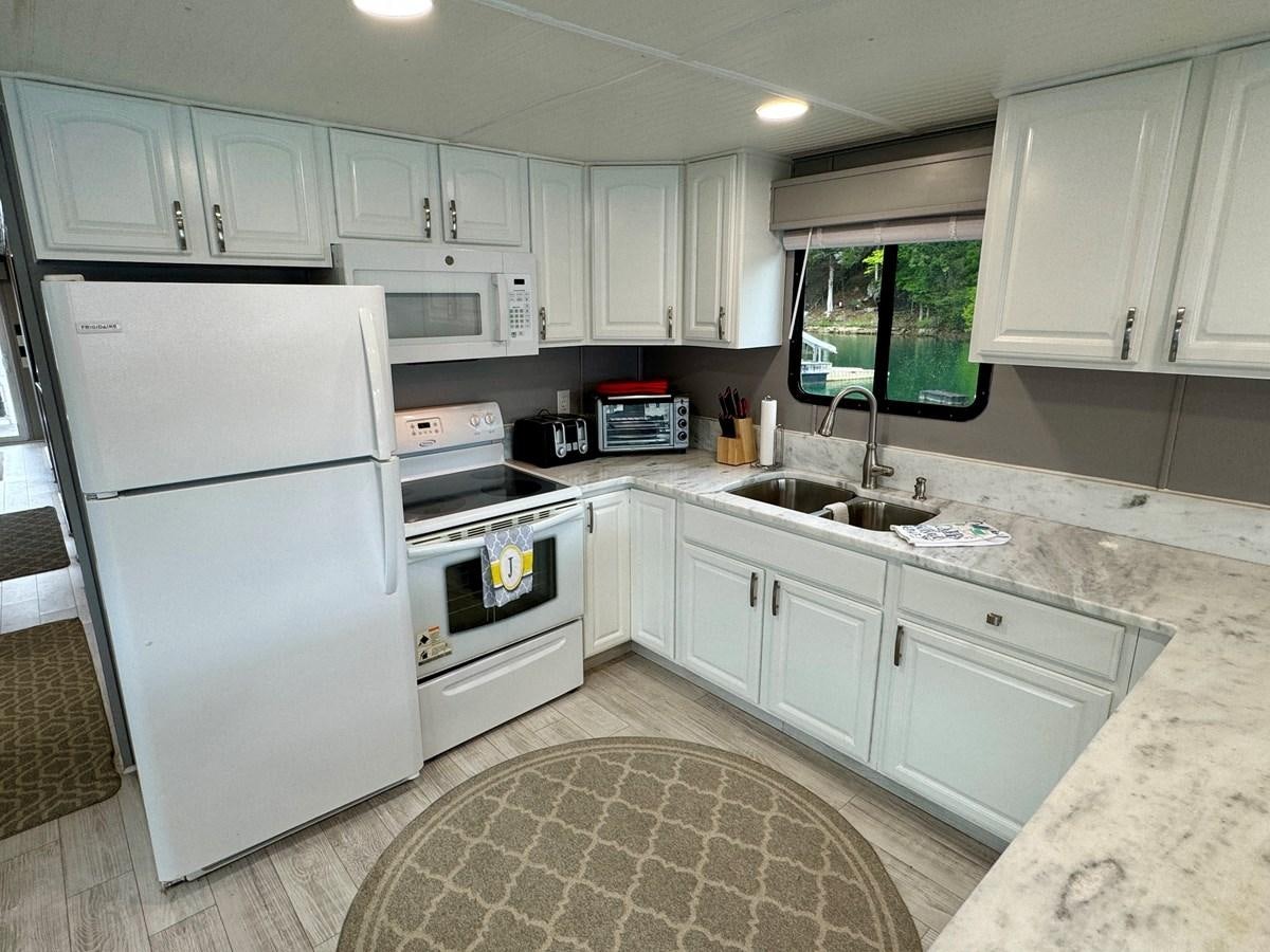 a kitchen with white cabinets aboard 2012 MAJESTIC 16 X 75WB HOUSEBOAT NLSD Yacht for Sale