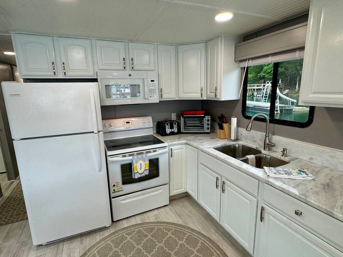 a kitchen with white cabinets aboard 2012 MAJESTIC 16 X 75WB HOUSEBOAT NLSD Yacht for Sale