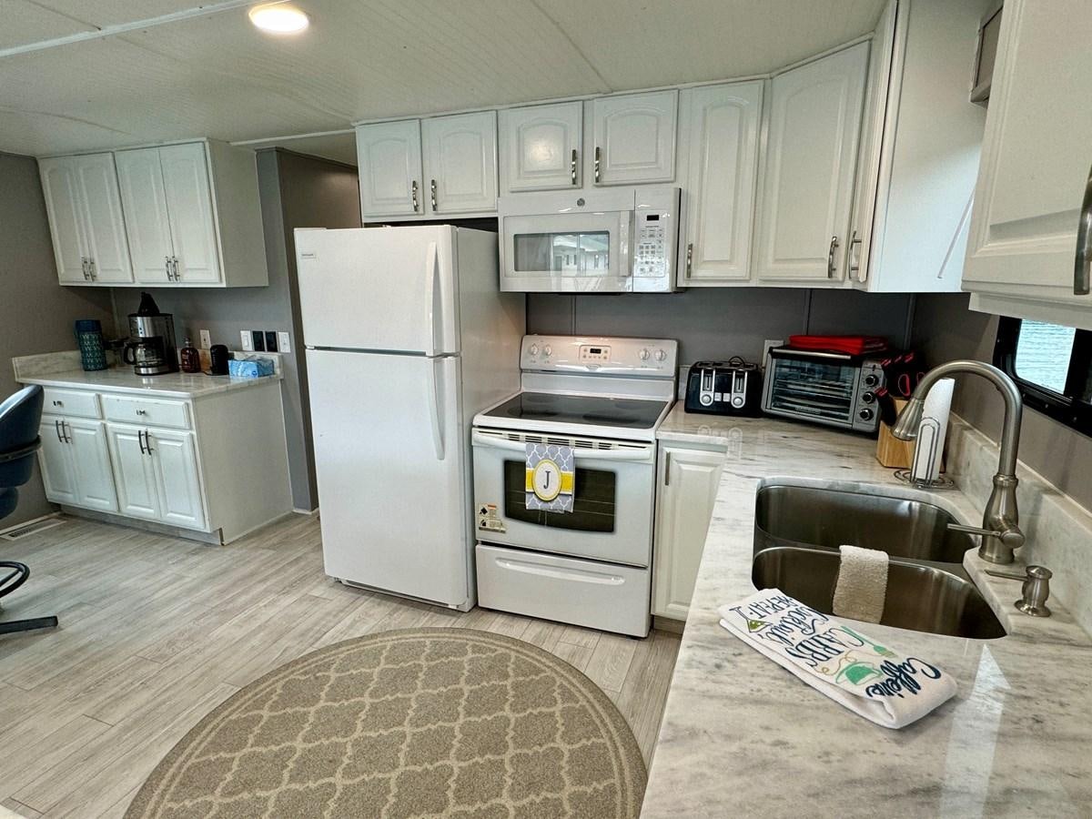 a kitchen with white cabinets aboard 2012 MAJESTIC 16 X 75WB HOUSEBOAT NLSD Yacht for Sale