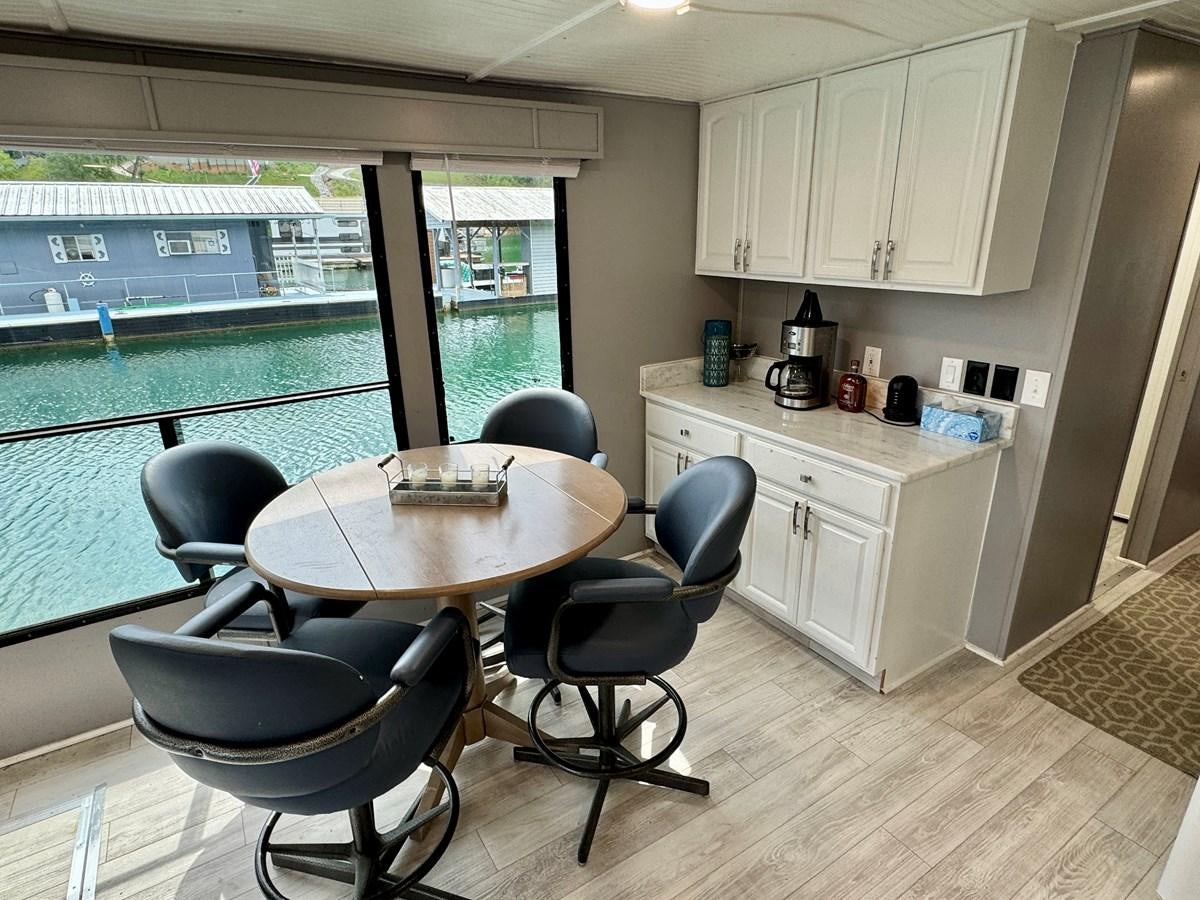 a kitchen with a table and chairs aboard 2012 MAJESTIC 16 X 75WB HOUSEBOAT NLSD Yacht for Sale