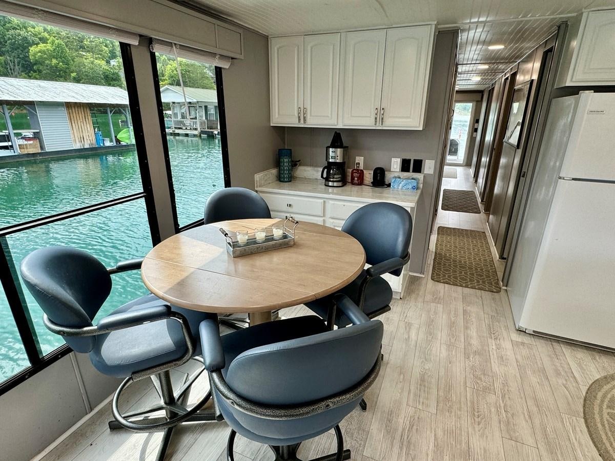 a kitchen with a table and chairs aboard 2012 MAJESTIC 16 X 75WB HOUSEBOAT NLSD Yacht for Sale