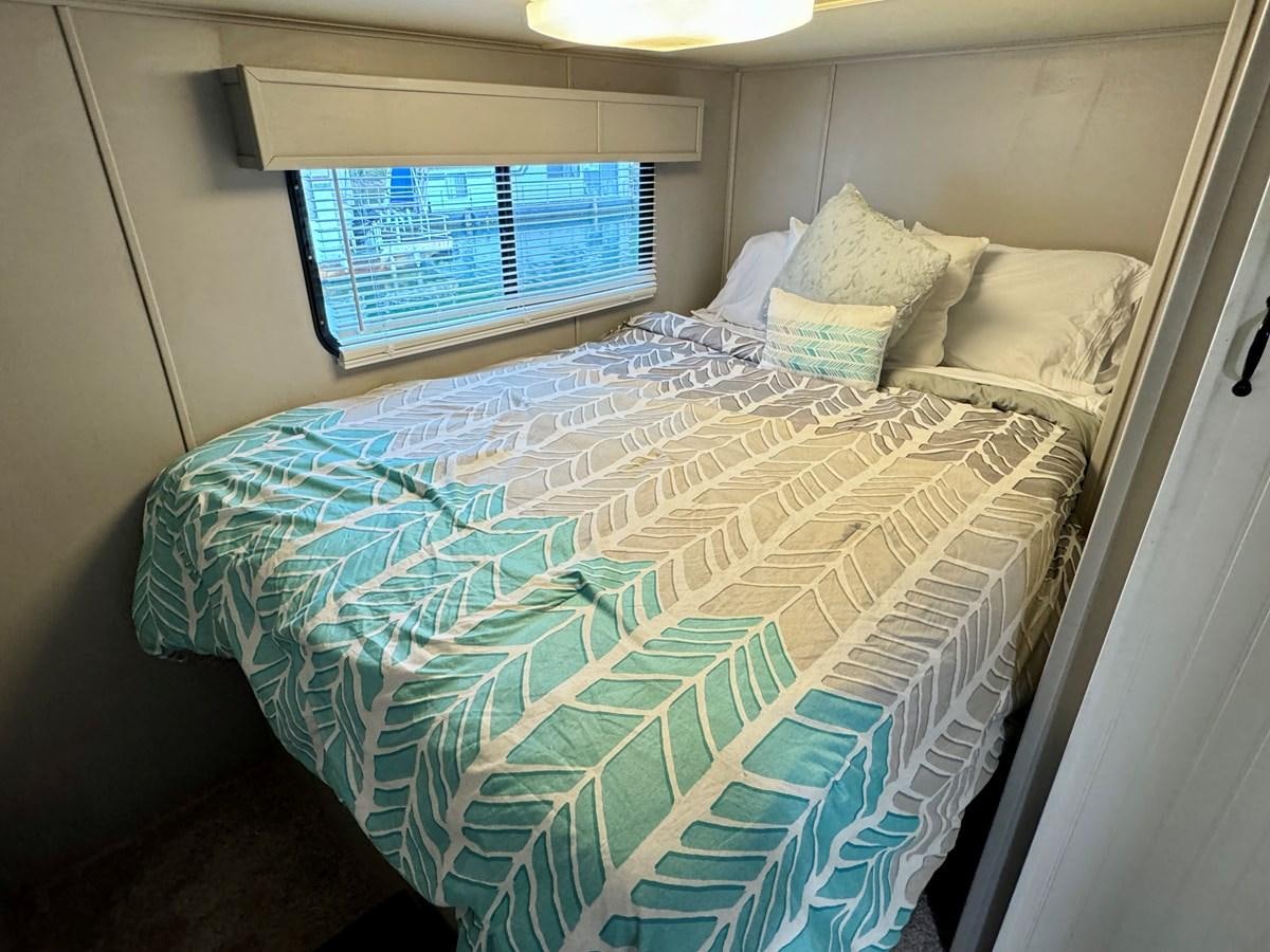 a bed with a blue comforter aboard 2012 MAJESTIC 16 X 75WB HOUSEBOAT NLSD Yacht for Sale