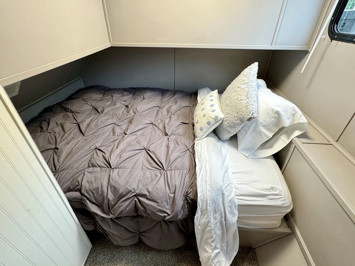 a room with a bed and a white trash can aboard 2012 MAJESTIC 16 X 75WB HOUSEBOAT NLSD Yacht for Sale