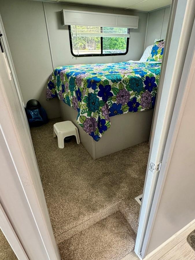 a room with a bed and a window aboard 2012 MAJESTIC 16 X 75WB HOUSEBOAT NLSD Yacht for Sale