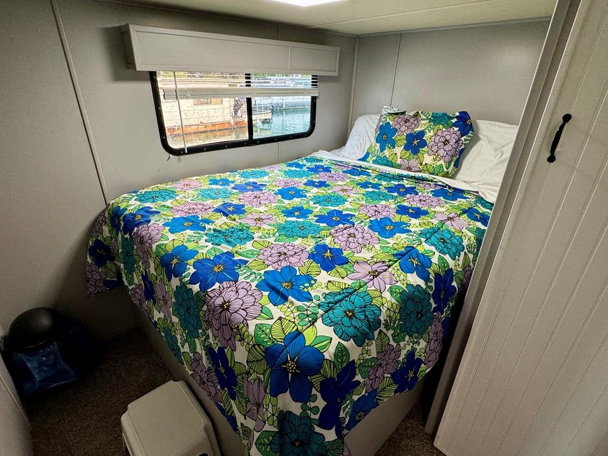a bed with a flowered comforter aboard 2012 MAJESTIC 16 X 75WB HOUSEBOAT NLSD Yacht for Sale