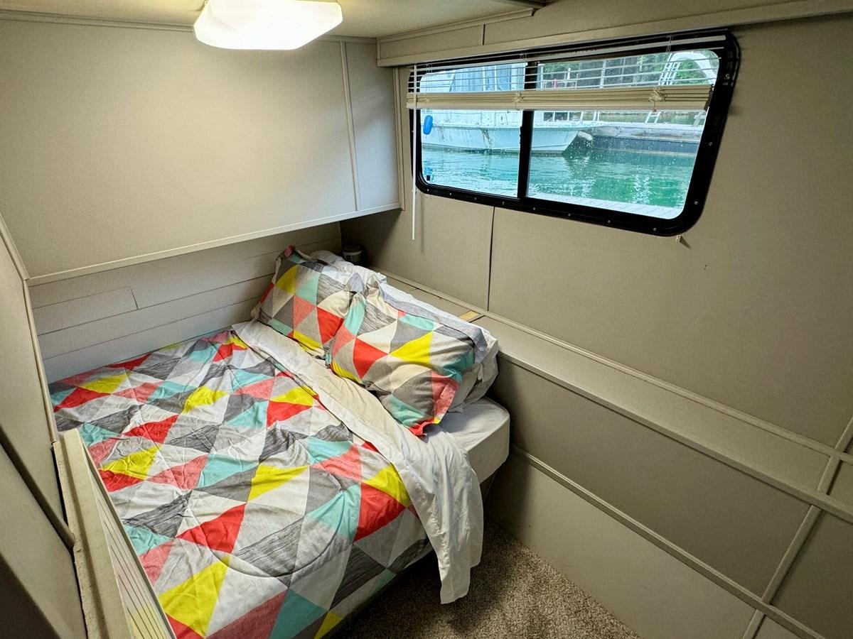 a small bedroom with a bed aboard 2012 MAJESTIC 16 X 75WB HOUSEBOAT NLSD Yacht for Sale