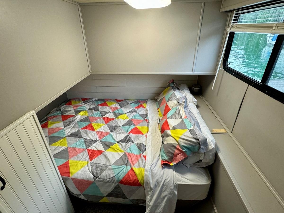 a room with a bed and a window aboard 2012 MAJESTIC 16 X 75WB HOUSEBOAT NLSD Yacht for Sale