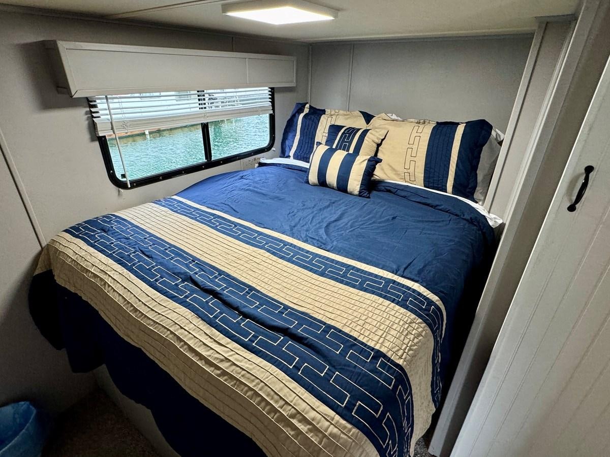 a bed with blue and white sheets aboard 2012 MAJESTIC 16 X 75WB HOUSEBOAT NLSD Yacht for Sale
