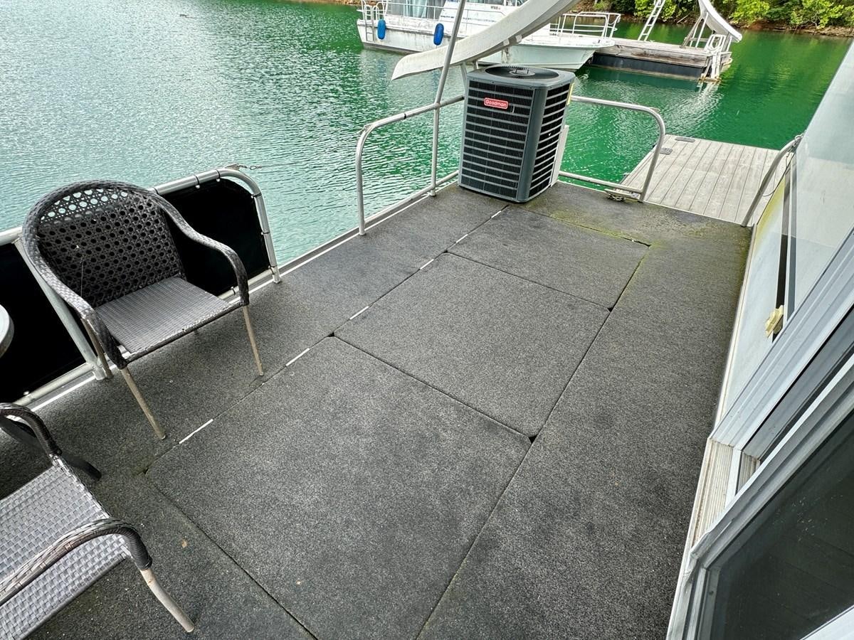 a chair on a deck by a pool aboard 2012 MAJESTIC 16 X 75WB HOUSEBOAT NLSD Yacht for Sale