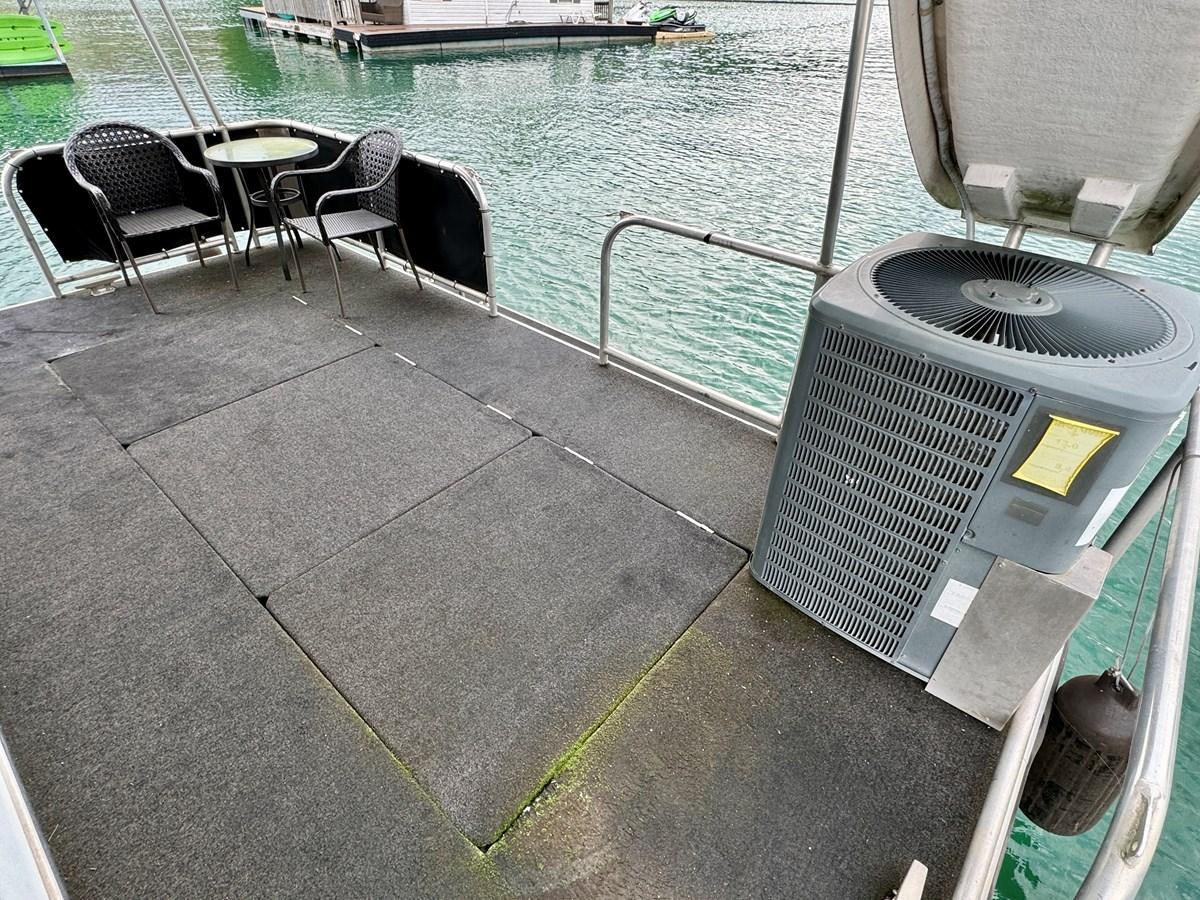 a chair on a deck next to a body of water aboard 2012 MAJESTIC 16 X 75WB HOUSEBOAT NLSD Yacht for Sale
