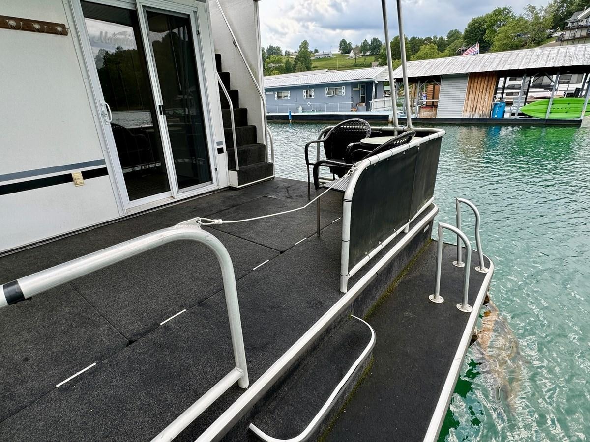 a boat with a chair on it aboard 2012 MAJESTIC 16 X 75WB HOUSEBOAT NLSD Yacht for Sale