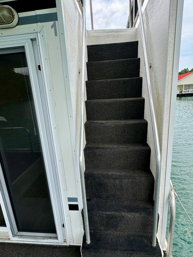 a black staircase with a white railing aboard 2012 MAJESTIC 16 X 75WB HOUSEBOAT NLSD Yacht for Sale