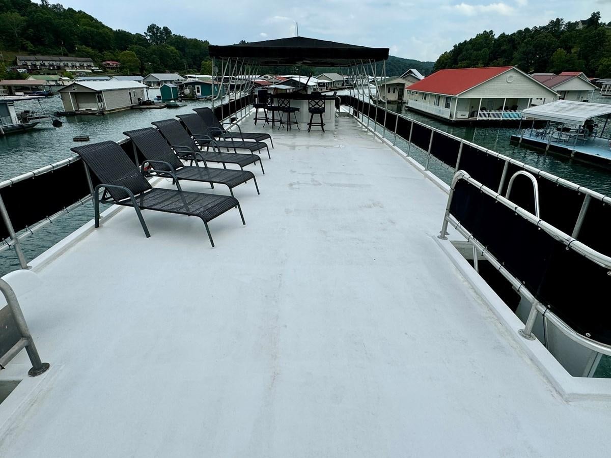 a deck with chairs and tables on it aboard 2012 MAJESTIC 16 X 75WB HOUSEBOAT NLSD Yacht for Sale