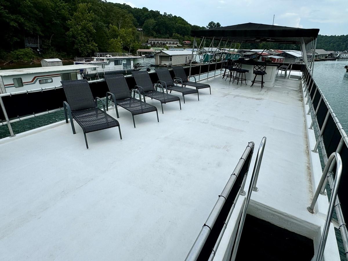 a deck with chairs and tables on it aboard 2012 MAJESTIC 16 X 75WB HOUSEBOAT NLSD Yacht for Sale