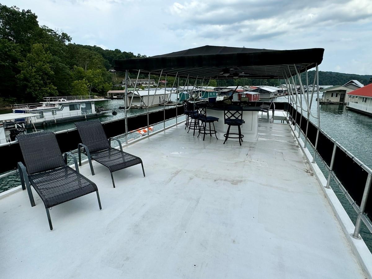 a deck with chairs and tables on it aboard 2012 MAJESTIC 16 X 75WB HOUSEBOAT NLSD Yacht for Sale
