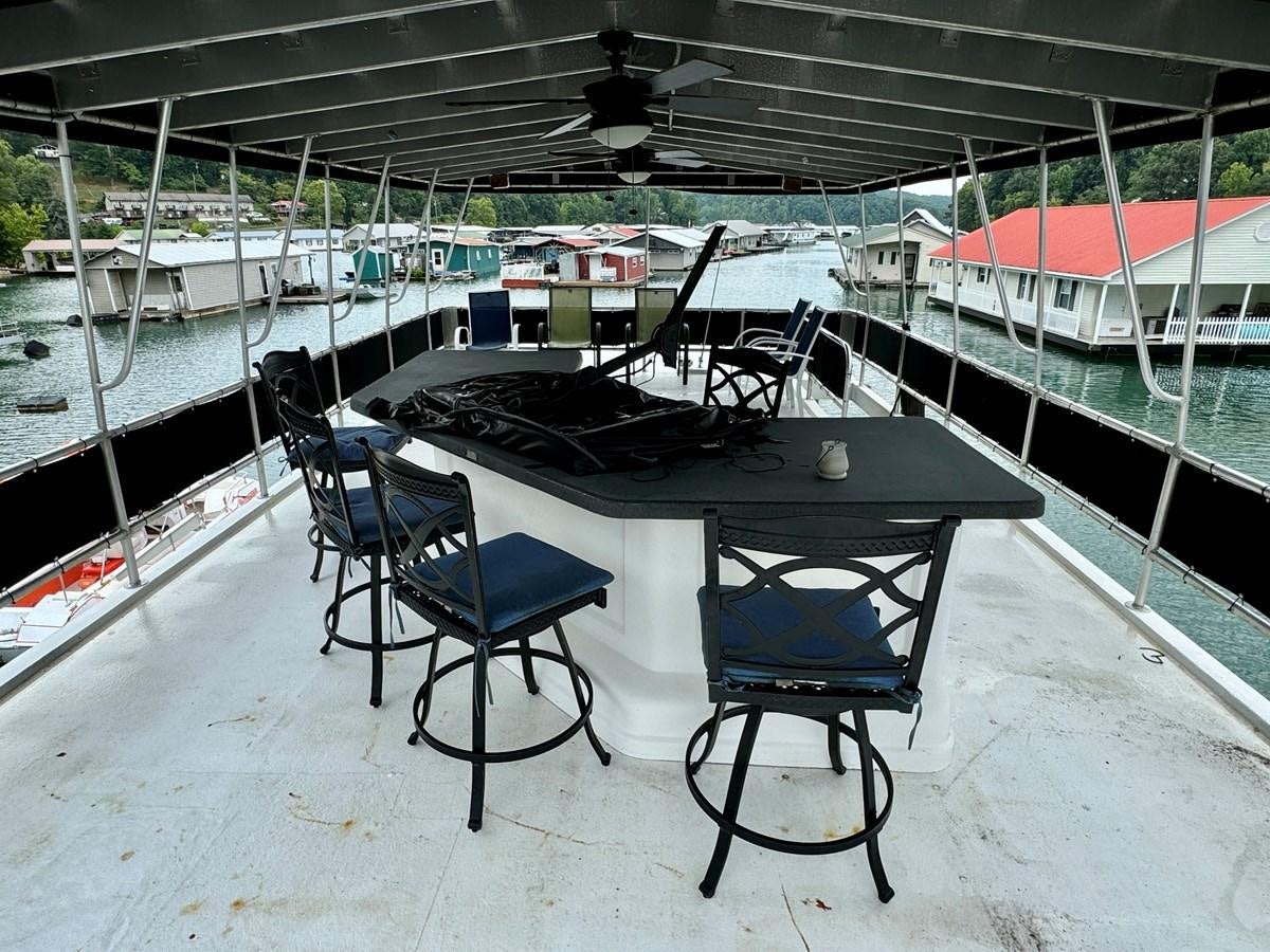 a table and chairs on a deck aboard 2012 MAJESTIC 16 X 75WB HOUSEBOAT NLSD Yacht for Sale