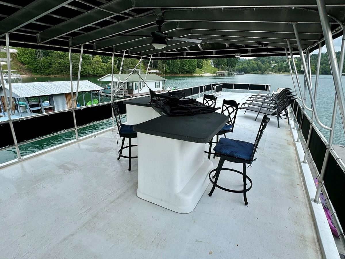 a table and chairs on a deck aboard 2012 MAJESTIC 16 X 75WB HOUSEBOAT NLSD Yacht for Sale