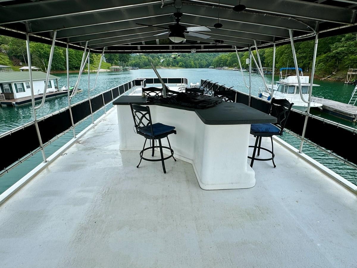 a chair on a deck aboard 2012 MAJESTIC 16 X 75WB HOUSEBOAT NLSD Yacht for Sale