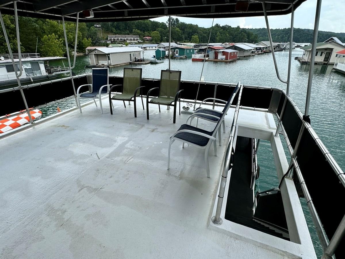 a deck with chairs and tables aboard 2012 MAJESTIC 16 X 75WB HOUSEBOAT NLSD Yacht for Sale