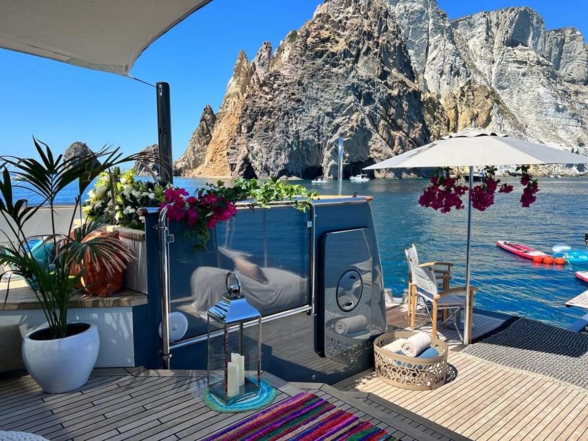 a table with a chair and umbrellas by a pool aboard ZULU Yacht for Sale