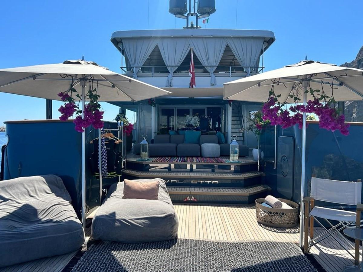 a lounge area with a lounge chair and umbrellas aboard ZULU Yacht for Sale