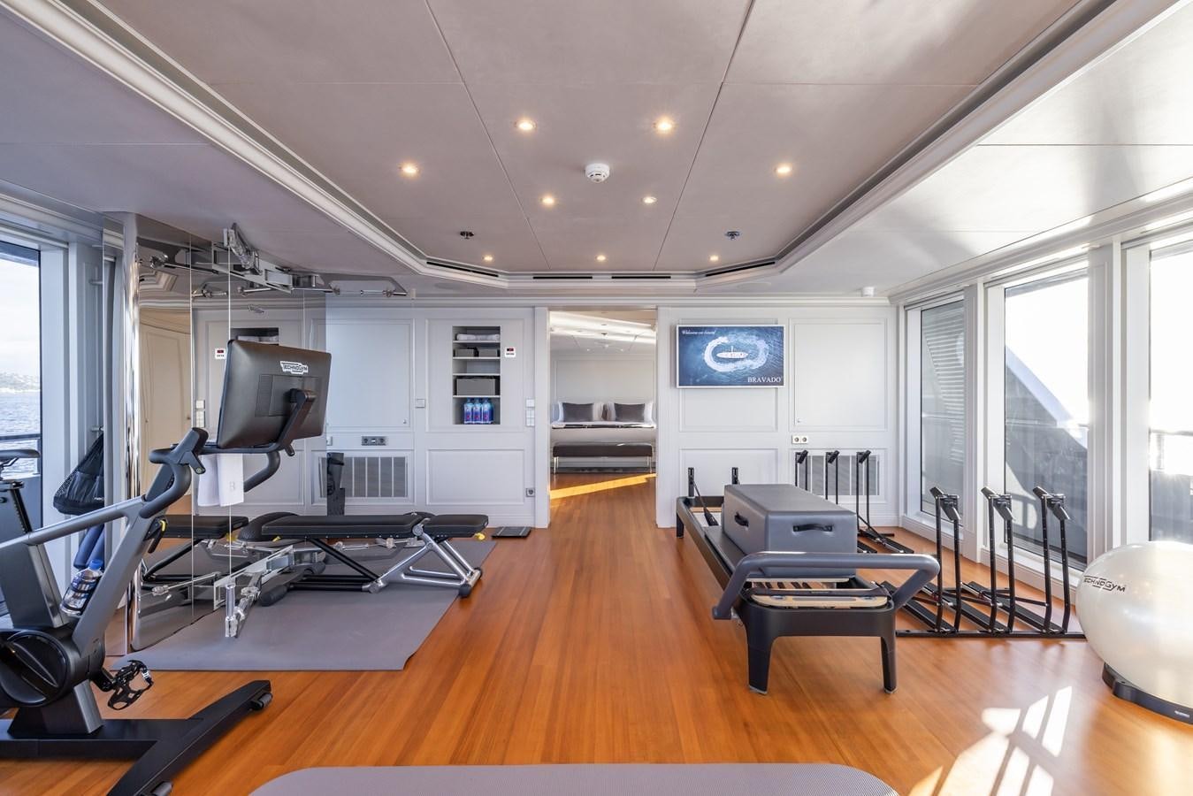 a room with a large mirror and a table with chairs and a television aboard BRAVADO Yacht for Sale