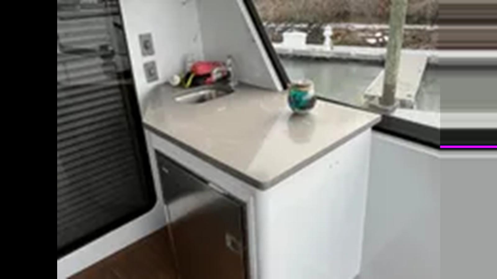 a kitchen sink with a plant in the window aboard 1999 HATTERAS 74 SPORT DECK MOTOR YACHT Yacht for Sale