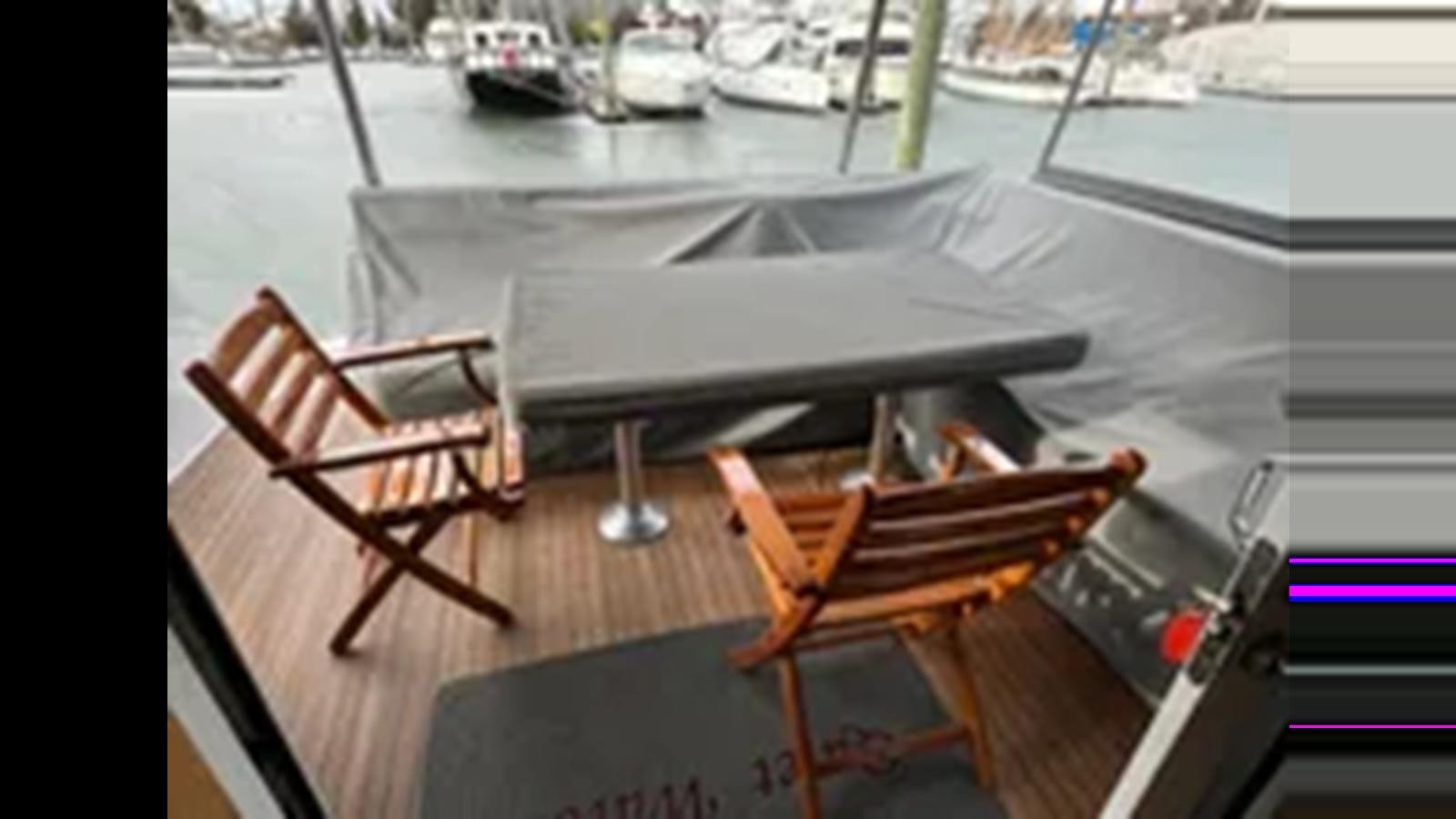 a table and chairs on a patio aboard 1999 HATTERAS 74 SPORT DECK MOTOR YACHT Yacht for Sale