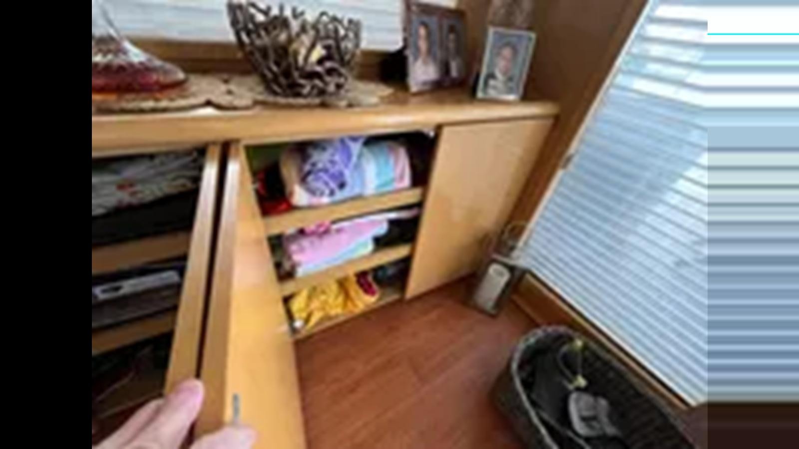 a person's hand holding a box with a shelf of clothes and a shelf with clothes and aboard 1999 HATTERAS 74 SPORT DECK MOTOR YACHT Yacht for Sale