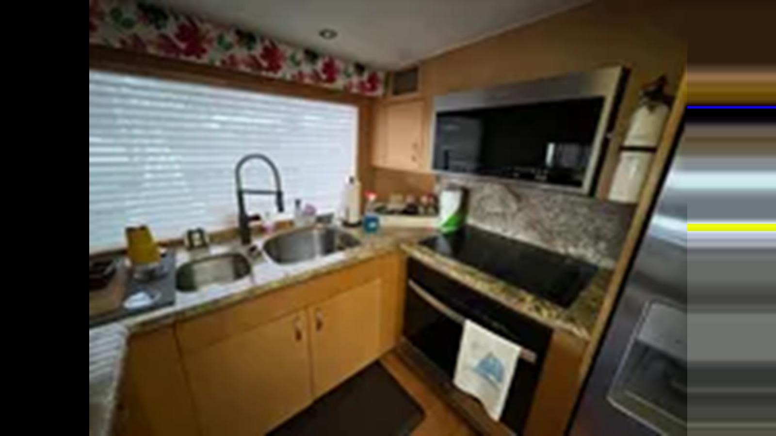 a kitchen with a sink and microwave aboard 1999 HATTERAS 74 SPORT DECK MOTOR YACHT Yacht for Sale