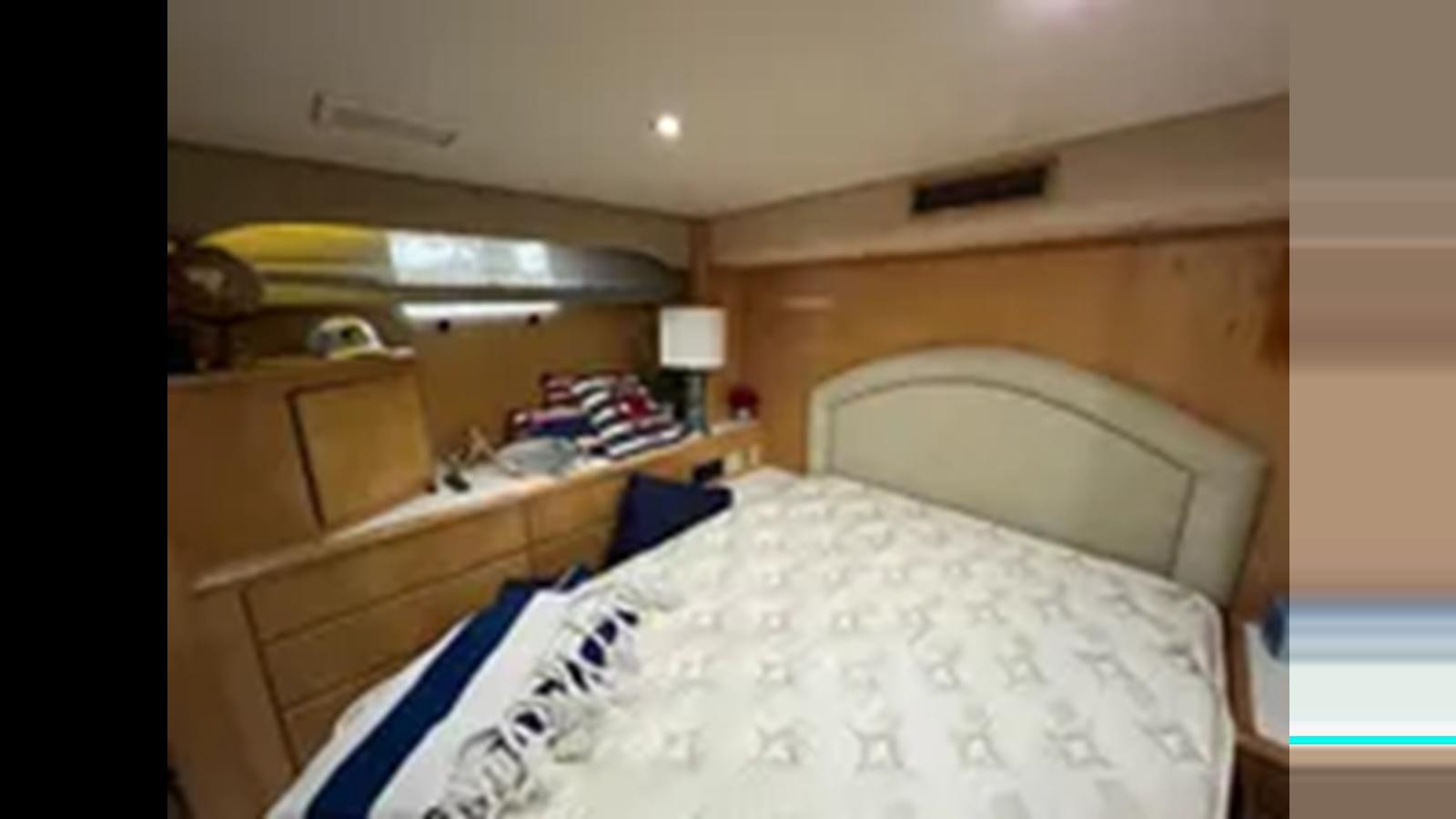 a room with a bed and a dresser aboard 1999 HATTERAS 74 SPORT DECK MOTOR YACHT Yacht for Sale
