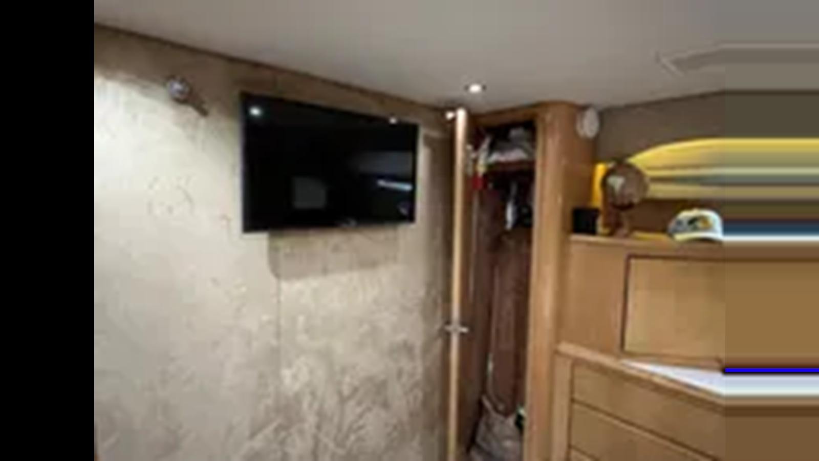 a room with a tv and cabinets aboard 1999 HATTERAS 74 SPORT DECK MOTOR YACHT Yacht for Sale